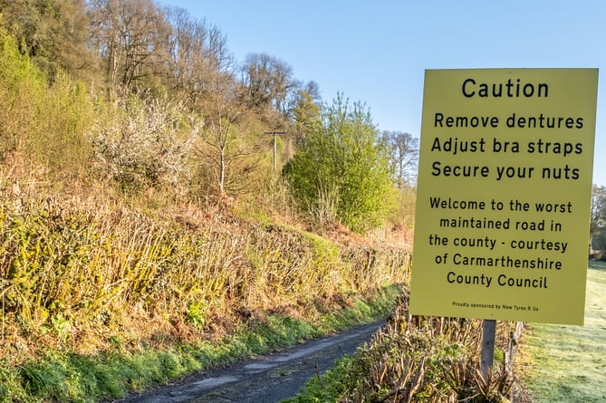 The sign near the Abergorlech Road in Carmarthenshire in Wales. See SWNS story SWLNpothole. Residents fed-up with potholes have installed a fake road sign warningÂ drivers toÂ 'adjust bra straps', 'remove dentures' and 'secureÂ their nuts'. Locals led by John Burton, 68, stuck up the hilarious sign claiming they are being 'ignored' by the council.The sign was put up yesterday (26/4) near the Abergorlech Road in Carmarthenshire in Wales.It says: "Caution. Remove dentures. Adjust bra straps. Secure your nuts.