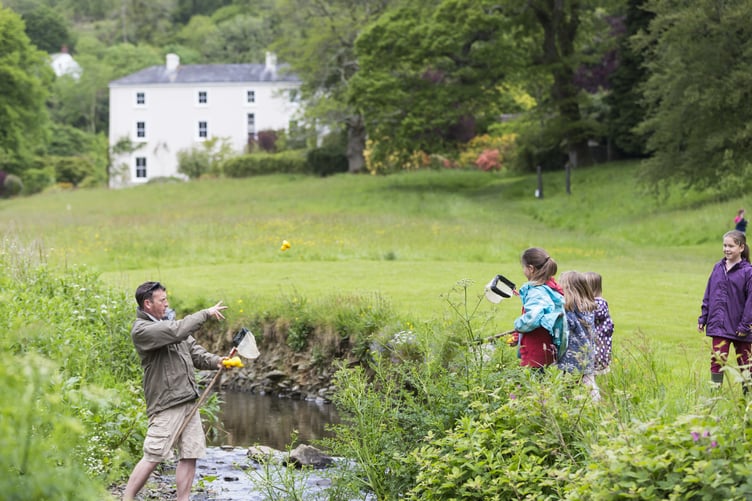 A family with fishing nets at the stream in the grounds of Colby Woodland Garden, Pembrokeshire. The garden is named after Welsh landowner John Colby (1751-1823), who originally came to the area in the 1790s to mine coal. Today, the woodland garden features a wild flower meadow, stream, and colourful walled garden.