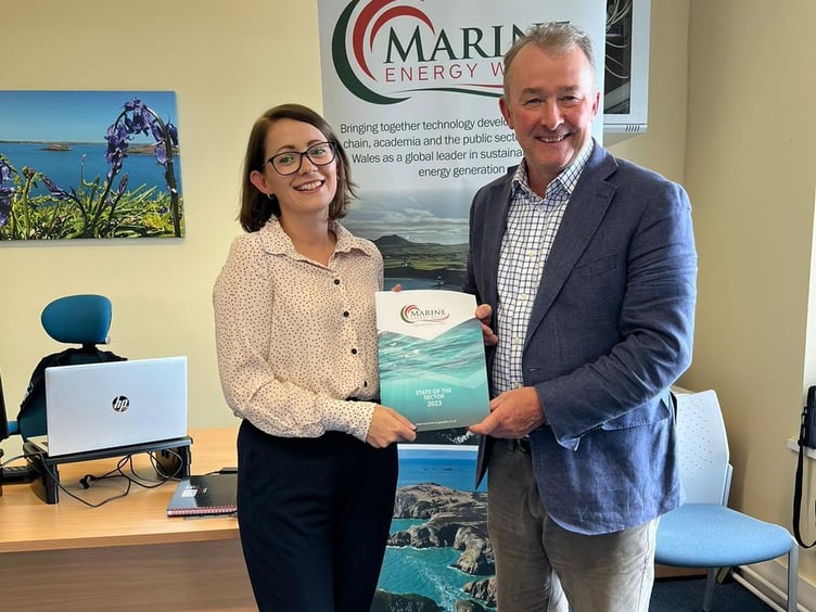 Simon Hart receives the Marine Energy Wales State of the Sector report from Communications Coordinator Jess Hill.