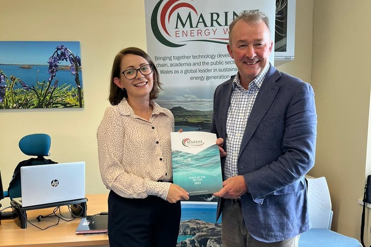 Simon Hart receives the Marine Energy Wales State of the Sector report from Communications Coordinator Jess Hill.