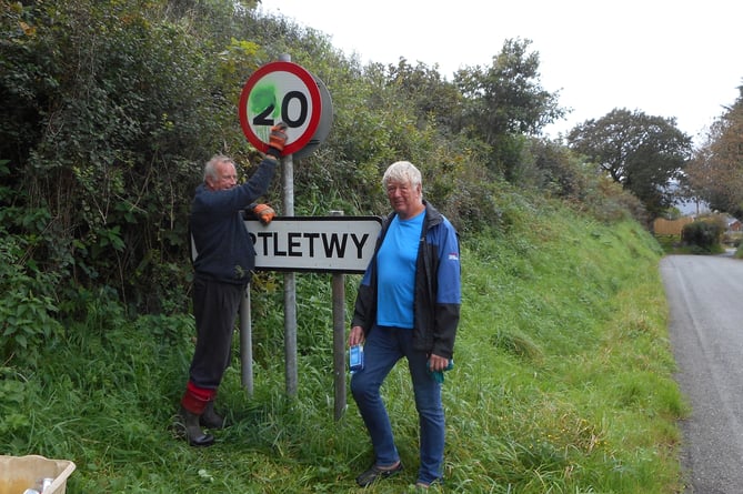 Two Martletwy residents Michael Carpenter and Geoffrey Sinclair cleaning a pair of the vandalised signs so that the figure 20 remains visible to oncoming traffic.