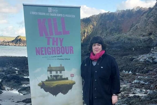 Artistic Director Chelsey Gillard with Kill Thy Neighbour play advertisement on Pembrokeshire beach.