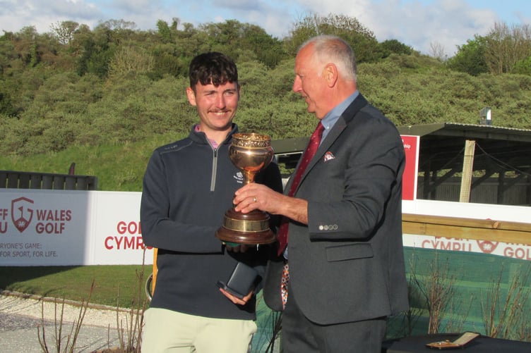 Champion Harry Watkins receiving the trophy from Tenby GC Captain Mick Seal.