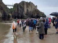 Sea baptism off a rainy Castle Beach in Tenby