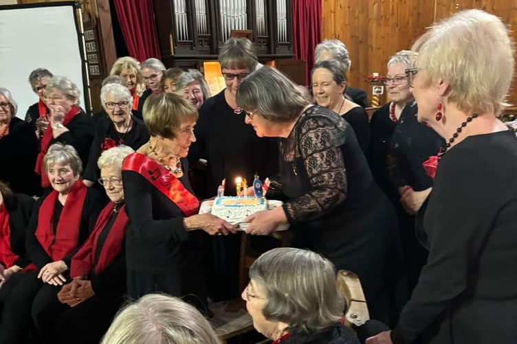 Neyland Ladies Choir chair Jayne Edwards presenting a birthday cake to 90-year-old chorister Dorothy