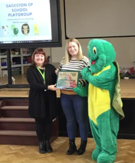 Mrs O’Leary receiving the Model Pre-School Award from Claire Sell and Twiggle from PATHS
