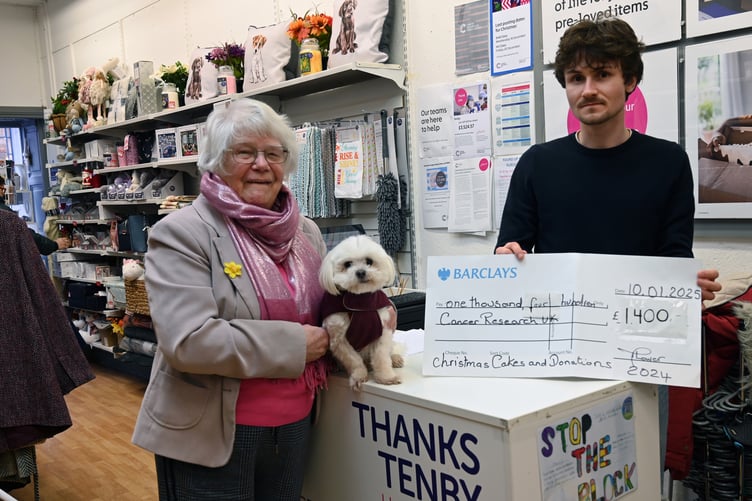 Cancer Research Tenby Shop Manager Ki Howells receives a cheque for £1,400 from Maureen Lower MBE, seen with dog Sammy.