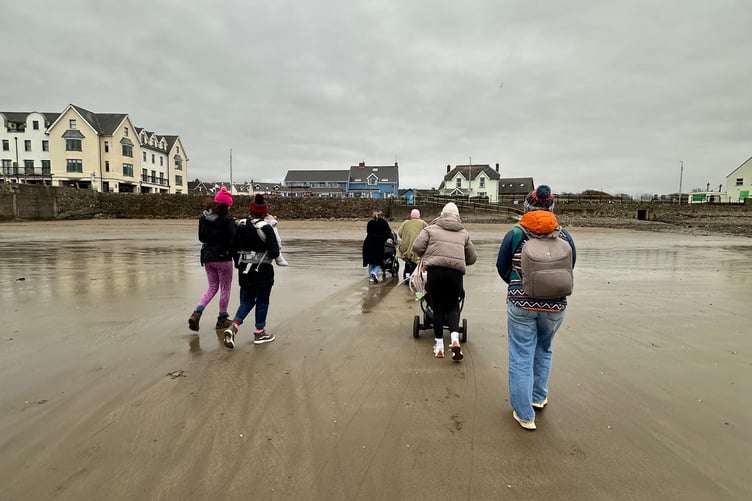 Parent and baby walking group strolling along Broad Haven beach in Pembrokeshire during a recent outing.
