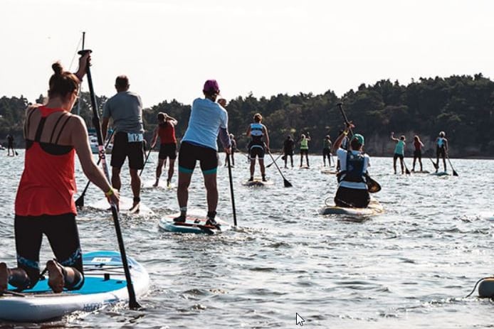 Contestants head out on paddle boards in the first stage of the triathlon