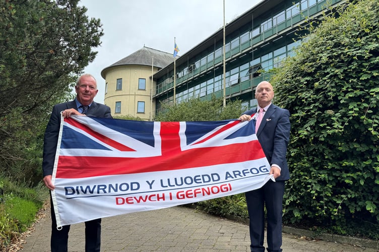 The Leader of Pembrokeshire County Council, Cllr Jon Harvey, left, and Cllr Simon Hancock, the Member Champion for Armed Forces, with the Armed Forces flag at County Hall. 