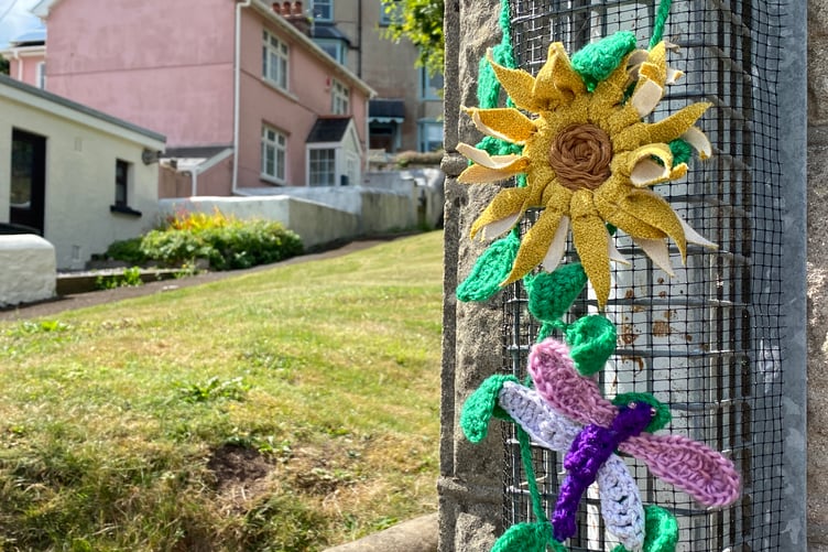 Beautiful yarn flowers and insects, created by Penally Yarn Bombers, grace the village bus stop.