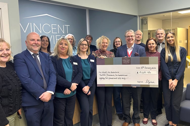 Staff from Vincent Davies Department Store with Mike May (holding the cheque) from the Wales Air Ambulance.