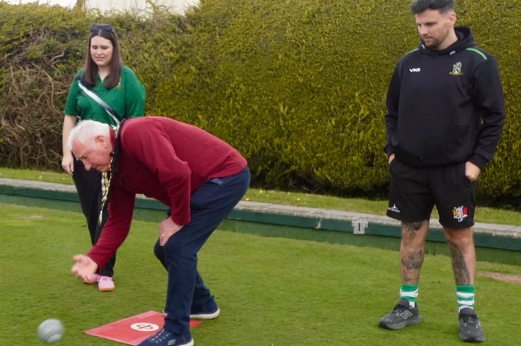 Watched by club captains, Katie Dickinson and Liam Price, Mayor of Whitland, Clr. Len Shipton, rolls the first wood to get the new season underway. 