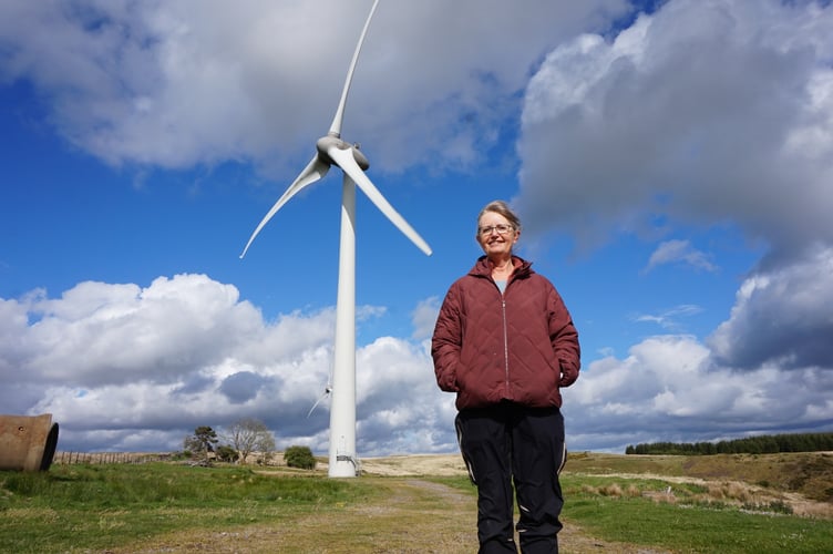 Emily Hinselwood in front of the two community-owned wind turbines at Awel Aman Tawe wind farm, above Cwmgors village.