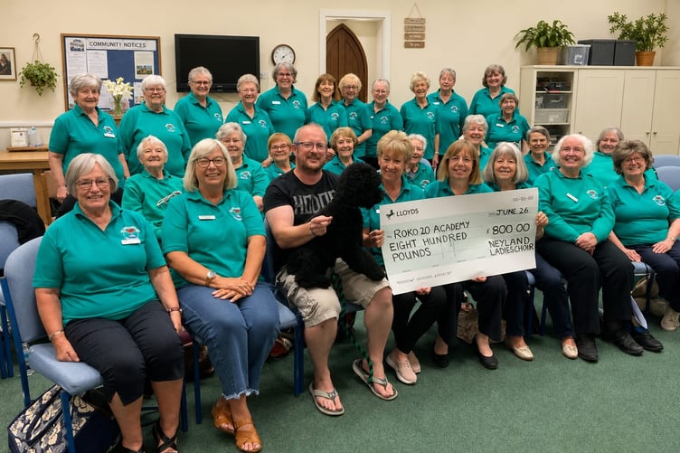 Jonny Sutton, accompanied by Ledley, receiving the cheque from Neyland Ladies Choir