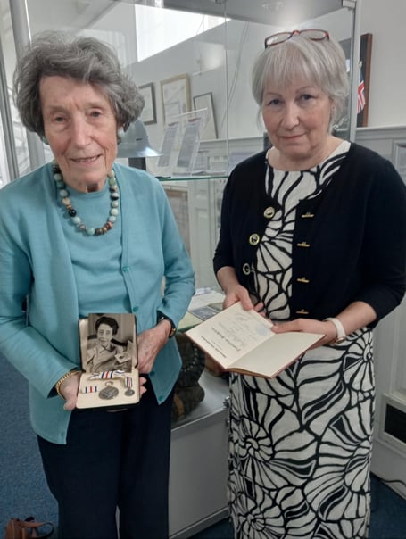Therese Burckhardt shows the King’s Medal, awarded to her grandmother, to Ruth Waddington at Pembroke Dock Heritage Centre.