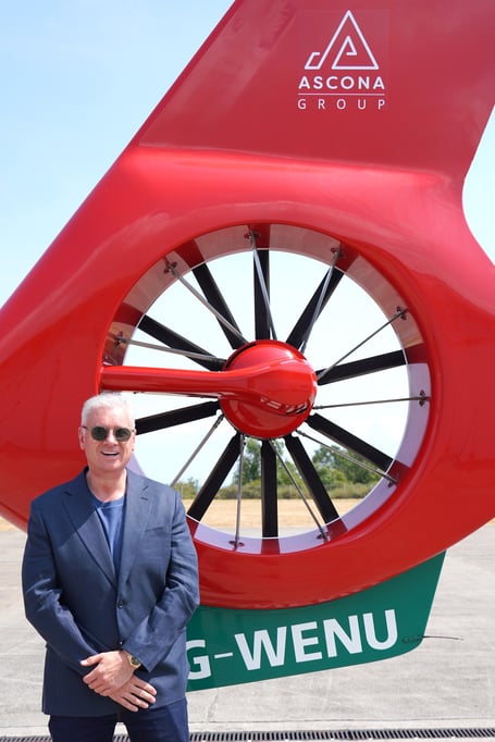 Ascona Group CEO Darren Briggs in front of the Wales Air Ambulance helicopter tail