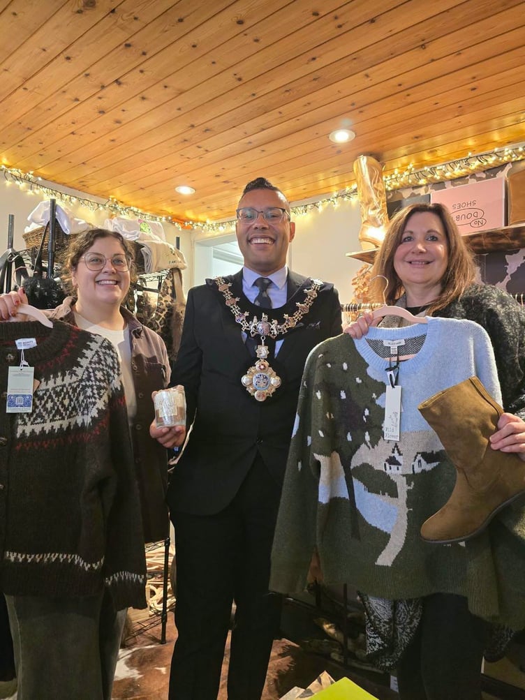 Cllrs Dani and Randell Thomas-Turner (wearing mayoral chain) with proprietor at Wild West, a shop in Quay Street, holding knitted garments etc.
