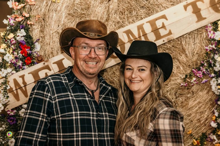 Couple in country-and-western-style clothing in front of hay